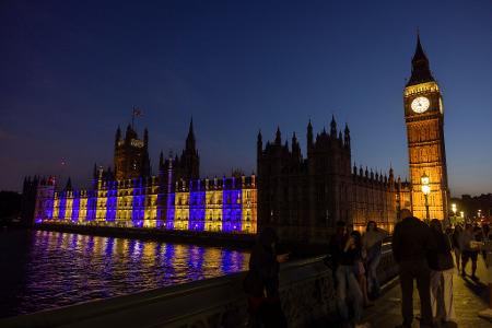 Der Westminster-Palast in London ist blau-gelb beleuchtet.