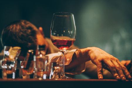 Besoffener Mann legt Kopf auf Tisch mit halbleeren Alkoholgläsern