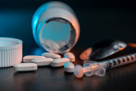 Pillen liegen neben einer Pillendose und Spritze