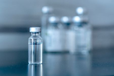 Flüssigkeit einer Glasphiole, im Hintergrund weitere Phiolen