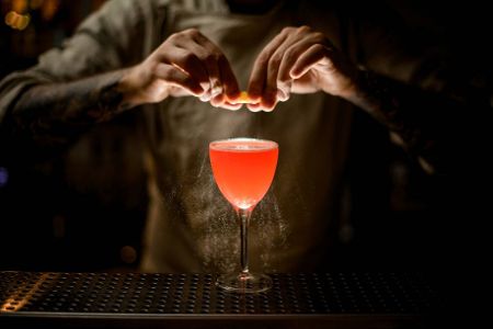 Mann streut eine Substanz in einen Cocktail
