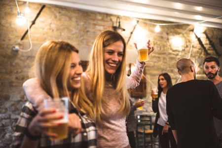 Zwei Frauen feiern eine Party, im Hintergrund sind Männer zu sehen