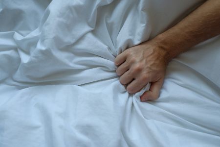 Männerhand greift nach Bettdecke
