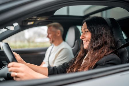 Frau am Steuer eines Autos, auf dem Beifahrersitz ein Mann.
