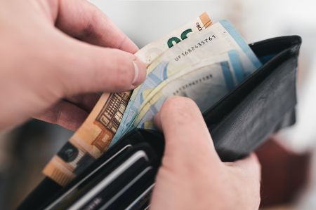 Mann holt Geldscheine aus einem Portemonnaie