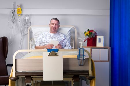 Mann sitzt aufrecht im Krankenhausbett