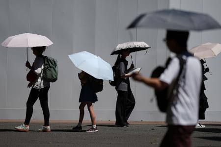 Mit Schirmen schützen sich Menschen vor der sengenden Sonne in Tokio.