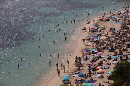 Menschen sonnen sich und entspannen am Meer am Strand von Caleta de Portals Nous auf Mallorca.
