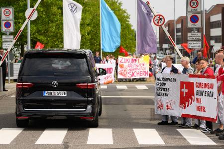 Ein VW-Bus mit VW-Vorstandschef Oliver Blume passiert die Demonstration von Beschäftigten am Werkstor des Standortes Zwickau. 