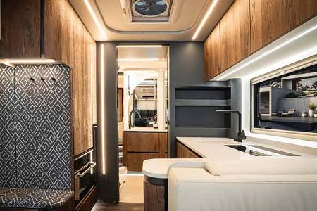 Innenraum Concorde Centurion 1100 GI: Hochwertige Küchenzeile mit Haushalts-Kühlschrank, Nappa-Leder, LED-Beleuchtung, Durchblick zum Wohnbereich.