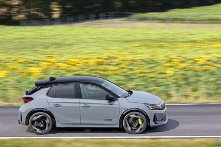 Das Bild zeigt einen Opel als fünftüriges Schrägheck in klarer Seitenansicht. Das Fahrzeug trägt ein sichtbares GSe-Badge und fährt auf einer Landstraße; Zweifarblackierung mit schwarzem Dach, große Leichtmetallfelgen und gelbe Bremssättel unterstreichen die sportliche Anmutung, der Mitzieher betont die Bewegung. Laut Dateiname stammt die Aufnahme aus August 2026.