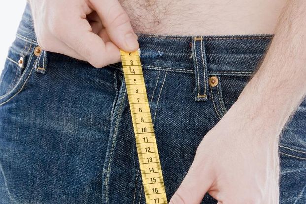 Mann mit Maßband vor der Hose im Schrittbereich