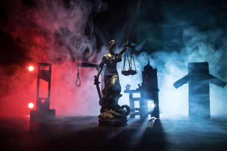 Figur von Justitia vor verschiedenen Geräten zur Vollstreckung der Todesstrafe