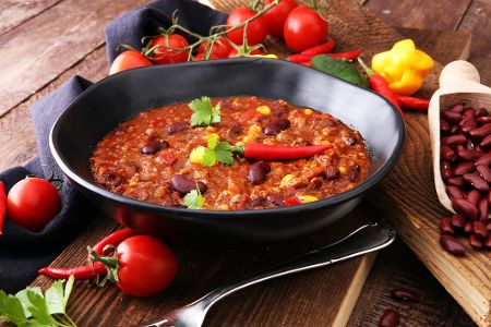 Chili in einer Pfanne, dekoriert mit Chilischoten und Tomaten
