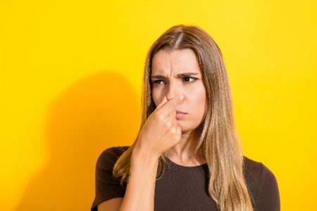 Frau hält sich die Nase zu