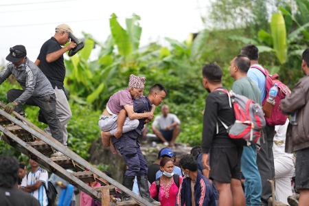 Ein Mann wird im Katastrophengebiet in Nepal von einem Polizisten auf dem Rücken getragen.