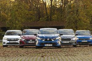 Fünf Kleinwagen-Modelle (Mitsubishi Colt, Dacia Sandero, Opel Corsa, Skoda Fabia, Hyundai i20) nebeneinander auf einem Parkplatz in herbstlicher Umgebung, frontal fotografiert.