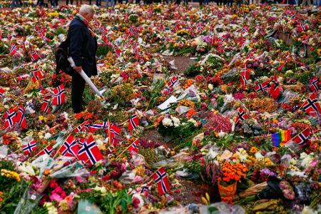 Ein Mann steht in Oslo zwischen den Blumengestecken für den verstorbenen norwegischen König Harald.