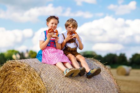 Zwei Kinder in bayerischer Tracht auf einem Strohballen
