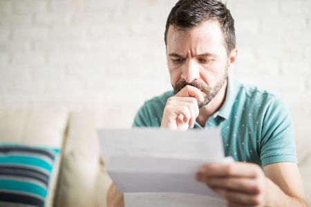 Mann sitzt nachdenklich vor einem Brief