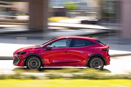 Renault Clio Full Hybrid E-Tech 160 in Rot, fahrend in urbaner Umgebung, Seitenansicht.