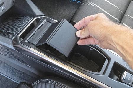 Detailaufnahme der Mittelkonsole eines Renault Clio Full Hybrid E-Tech 160 mit offener Ablage und Hand.