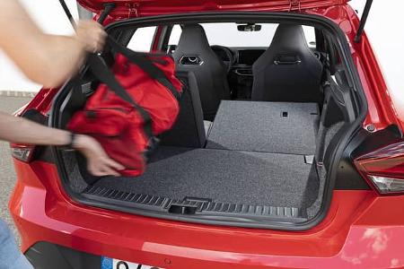 Der geöffnete Kofferraum eines Seat Ibiza TSI mit umgeklappter Rückbank. Eine Person lädt eine rote Tasche ein.