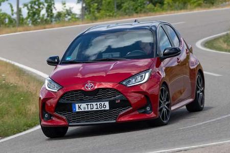Toyota Yaris Hybrid auf kurviger Landstraße, rote Lackierung, sportliche Front, Tageslichtaufnahme.