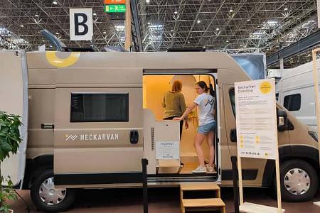 Neckarvan Coastline in Beige auf dem Caravan Salon Düsseldorf 2026, Seitenansicht mit geöffneter Schiebetür, Blick ins helle Interieur.