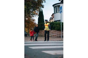 Polizistin führt Kinder über einen Zebrastreifen