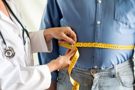 Arzt misst übergewichtigem Patienten den Bauchumfang