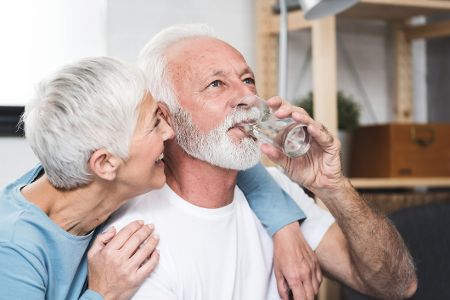 Älteres Ehepaar, wo er ein Glas Wasser trinkt