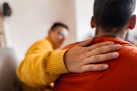 Mann legt einem anderen unterstützend die Hand auf die Schulter