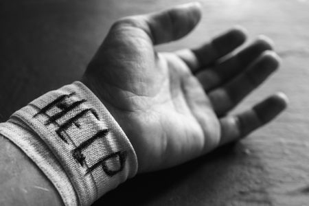Hand mit bandagiertem Handgelenk, auf dem Help steht