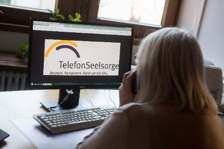 Frau sitzt vor Webseite der Telefonseelsorge und telefoniert