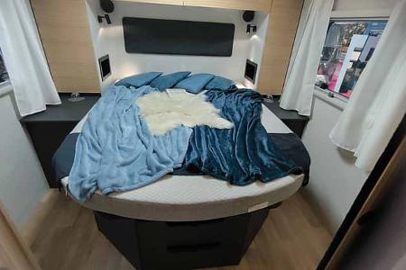 Queensbett im Heckbereich des vollintegrierten Mooveo INT-78 QBF Al-Ko. Großzügiger Schlafplatz mit Stauraum und moderner Innenraumgestaltung.