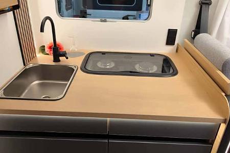 Küchenblock mit Herd und Spülbecken im Mooveo INT-78 QBF Al-Ko. Hochwertige Arbeitsplatte und moderne Armaturen für komfortables Kochen.