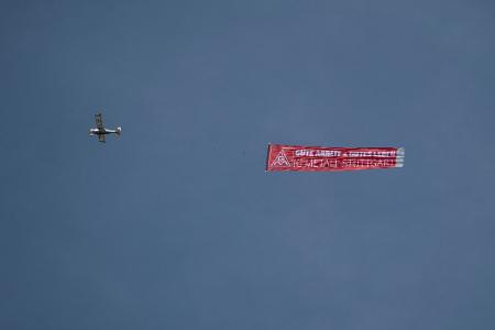 Ein Flugzeug mit einem IG-Metall-Banner fliegt über das Porsche-Stammwerk in Zuffenhausen.