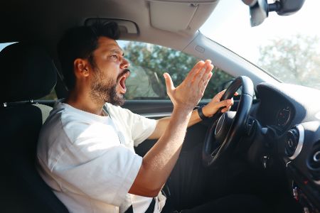 Fluchender Mann hinterm Steuer im Auto