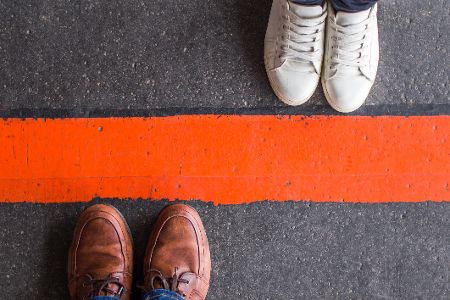 Männliches und weibliches Paar Schuhe stehen auf unterschiedlichen Seiten einer roten Linie
