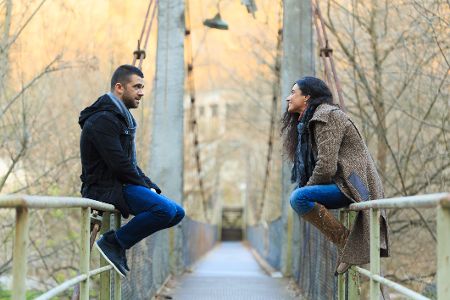 Pärchen sitzt auf dem Geländer einer Brücke und unterhält sich