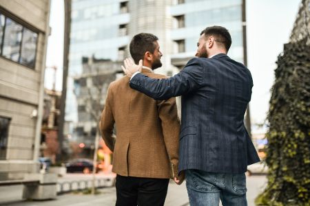 Männliches Pärchen in Anzügen klopft sich gegenseitig auf die Schulter