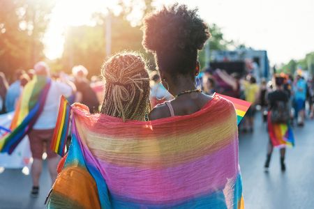 Weibliches Pärchen mit Regenbogentuch auf der Straße