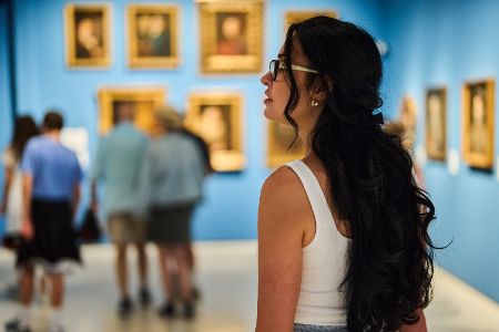 Frau schaut in einem Museum ein Gemälde an