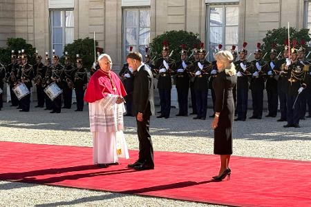 Frankreichs Präsident Emmanuel Macron und seine Ehefrau Brigitte schütteln Hände mit dem Papst im Hof des Élysée-Palastes.