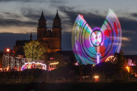 Das Fahrgeschäft "Eclipse" dreht sich am Abend vor dem Magdeburger Dom auf der 1016. Magdeburger Herbstmesse.