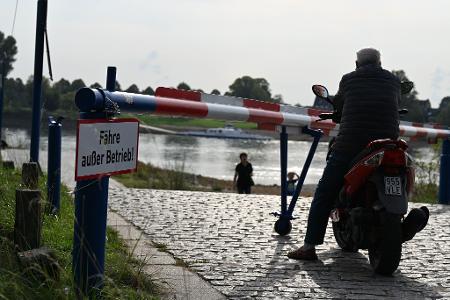 Das Warten auf die Fähre ist vergeblich: Ein Motorroller-Fahrer blickt einige Minuten auf den Rhein, dann kehrt er um und fährt davon. (Archivbild)