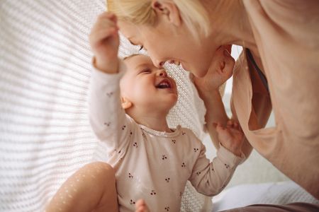 Baby spielt mit seiner Mutter unter einer Decke