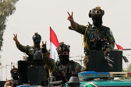Mit Siegeszeichen: Irakische Sicherheitskräfte fahren in einem Konvoi durch die irakische Hauptstadt, um den vollständigen Abzug der US-Truppen aus dem Irak zu feiern.