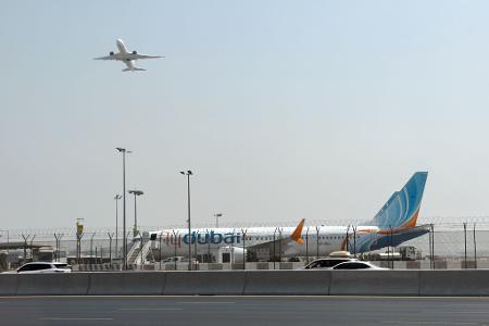 Ein Flugzeug hebt ab, während ein Flydubai-Flieger in Dubai auf dem Flughafen steht. 